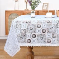 a table with a white doily on it in front of a wooden cabinet and flowers