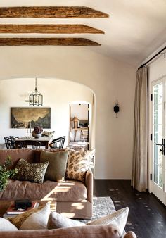 a living room filled with lots of furniture next to a dining room table and chairs