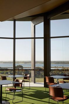 an empty restaurant with large windows overlooking the ocean and grass on the floor is very nice