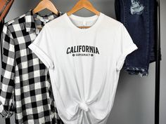 Discover a classic piece with our California Supremacy T-Shirt. This tee features a vintage-inspired design perfect for those who love California vibes. Its retro look makes it a great casual wear choice for any fan of the West Coast. Comfortable and stylish, this shirt is a must-have for your collection. Ideal for everyday wear or as a gift for California enthusiasts. Celebrate the spirit of California with this unique graphic tee. Product Features: Fabrication: 100% Airlume combed and ring-spun cotton, 32 single 4.2 oz. (Ash - 99% Airlume combed and ring-spun cotton, 1% poly) Seams: Side-seamed Fit: Retail Fit Sizing: Unisex Sizing Label: Tear away label California Graphic, West Coast Style, West Coast Fashion, Coast Style, Vintage California, Graphic Top, Vintage Inspired Design, Style Shirt, Retro Look