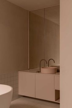 a white bath tub sitting next to a bathroom sink under a mirror in a bathroom