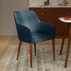 a blue chair sitting on top of a rug next to a table