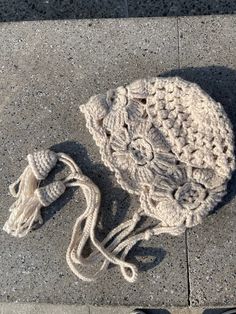 a crocheted hat laying on the ground next to someone's shoes