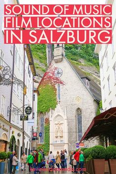 people are walking down the street in front of a building with a red sign that says sound of music film locations in saalburg