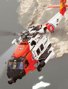 an orange and white helicopter flying over the ocean