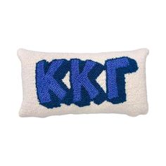 a white and blue pillow with the letter kt on it's side, in front of a white background