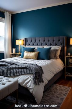 a bedroom with blue walls, white bedding and gray pillows on the headboard