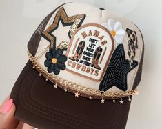 a woman holding up a hat with patches and chains on it's front side