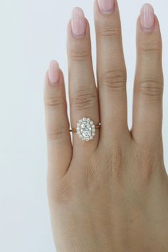 a woman's hand with a diamond ring on top of her left hand,