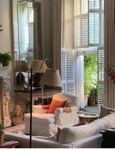 a living room filled with furniture and windows covered in shuttered glass doors that look out onto a garden