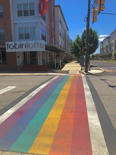 a rainbow painted crosswalk in the middle of a street with buildings on both sides