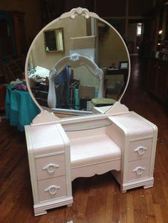 a white vanity with a mirror on top of it and a table in front of it