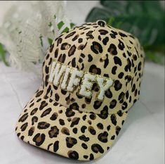 Rock this trendy Wifey Animal Print Hat on Game Day! Designed for true fans, this hat features a stylish animal print and a bold 'Wifey' patches. Trendy Leopard Print Cap, Leopard Hat, Tyler Candle Company, Louis Vuitton Hat, Kids Graphic Tees, Cricut Creations, Hidden Pocket, Kids Swimwear, Fashion Jewelry Earrings