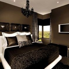 a large bed in a bedroom with a chandelier hanging from the ceiling and two framed pictures on the wall