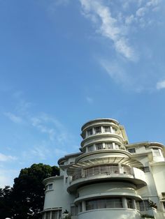 a tall white building with balconies on it's sides under a blue sky