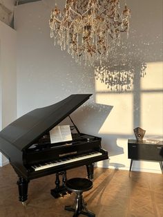 a grand piano sitting in front of a chandelier