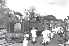 black and white photograph of people walking next to an old train