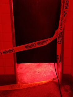 a red light room with caution tape wrapped around the door and on the floor next to it