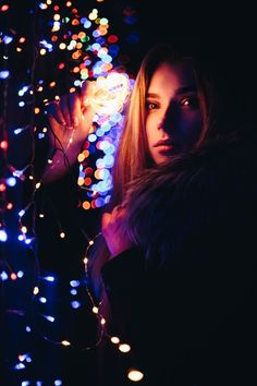 a woman standing in front of a bunch of lights with her hand on the wall