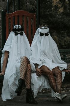 two women in white dresses sitting on a bench wearing black stockings and garters