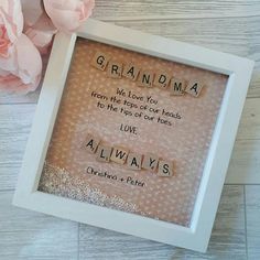 a white frame with words written in it and pink flowers on the floor next to it