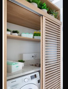 a washer and dryer in a small room with open shelves on the wall