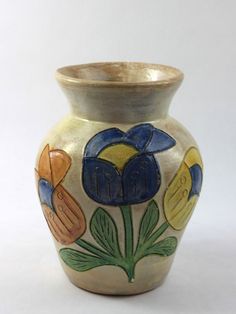 a ceramic vase with flowers painted on the outside and inside, sitting on a white surface