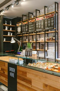 a restaurant counter with pizzas on display behind the counter and menu boards above it