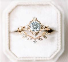 a close up of a ring on top of a white cloth covered box with a diamond in the center