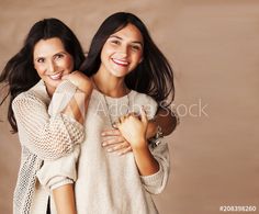 two beautiful young women posing for the camera with their arms around each other and smiling