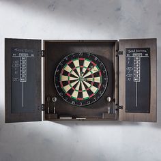 a dart in a wooden box with chalk writing on the wall behind it and an arrow pointing to the target