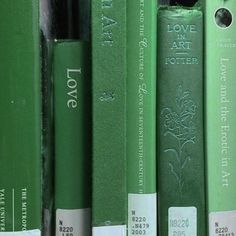 a row of green books sitting on top of a book shelf next to each other