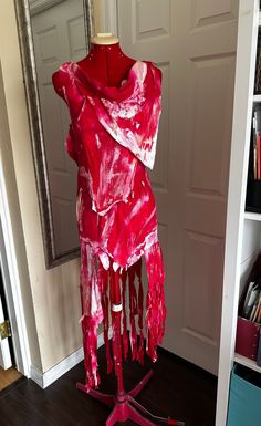 a red and white scarf on a mannequin stand in front of a door