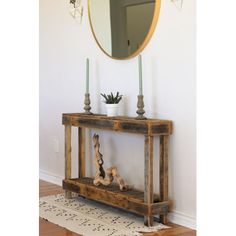 a wooden table sitting in front of a mirror on top of a floor next to a rug