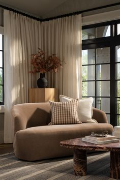 a living room filled with furniture next to large windows and a vase on top of a table