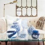 blue and white vases sitting on top of a glass table in front of a couch