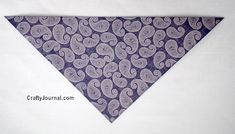 a purple and white bandana with paisley print on the front, sitting on a white surface