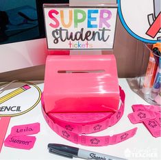 a pink box with some writing on it sitting next to a pen and paper stickers