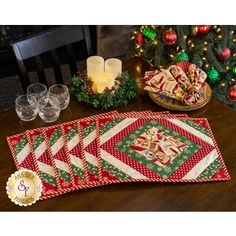 a table topped with plates and cups filled with christmas treats next to a lit candle