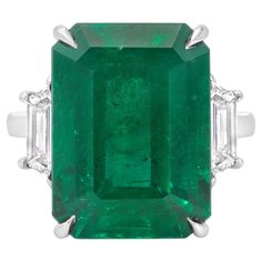 An elegant engagement ring, showcasing a C. Dunaigre certified 12.82 carats emerald cut green emerald, set on a classic four prong setting. Accented by two trapezoid cut diamonds weighing 1.02 carats total with D-E color and VS+ clarity. Elegantly made with a platinum mounting. Size 6.5, resizable upon request.  Roman Malakov is a custom house, specializing in creating anything you can imagine. If you would like to receive a special quote on a custom piece, please message or call us. Diamonds Direct, Emerald And Diamond Ring, Vintage Cocktail Ring, Elegant Engagement Rings, Colombian Emeralds, Three Stone Engagement, Three Stone Engagement Rings, Diamond Gold, Platinum Ring