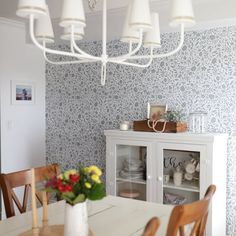 a dining room table and chairs in front of a wallpapered wall