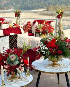 red and white flowers are in vases on the coffee table next to couches