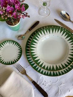 a green and white plate sitting on top of a table next to a vase with purple flowers