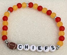 Support the Chiefs year-round with this cute, lightweight bracelet! Made with round beads, silver rhinestone spacers and a football charm.   For sizing help:  6 inches is considered a child or an adult X-small wrist. 6.5 inches is considered an adult small wrist. 6.75 inches is considered an adult medium wrist. 7 inches is considered an adult large wrist. 7.25 inches is considered an adult X-large wrist. Red Beaded Charm Bracelet For Friendship, Personalized Orange Round Bead Jewelry, Red Letter Beads Jewelry, Red Jewelry With Round Letter Beads, Adjustable Red Name Bracelet With Round Beads, Red Beaded Name Bracelet With Round Beads, Red Beaded Name Bracelet, Personalized Red Name Bracelet With Round Beads, Red Bracelets With Letter Beads