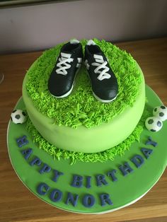 a green birthday cake with soccer shoes on top