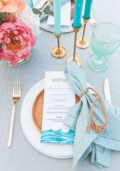 a place setting with blue napkins and gold candles