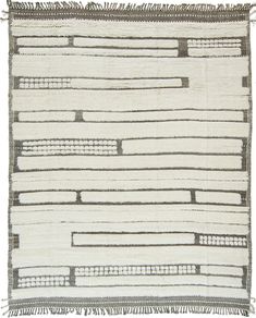 a white and grey rug with fringes on the bottom, in front of a white background