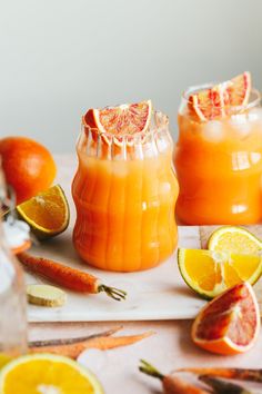 orange juice in jars with garnishes and fruit around them