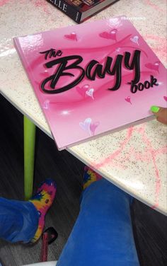 a person sitting at a table with a book on it's back and the words, the bayy book