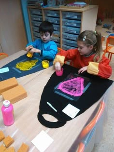 two children sitting at a table making art